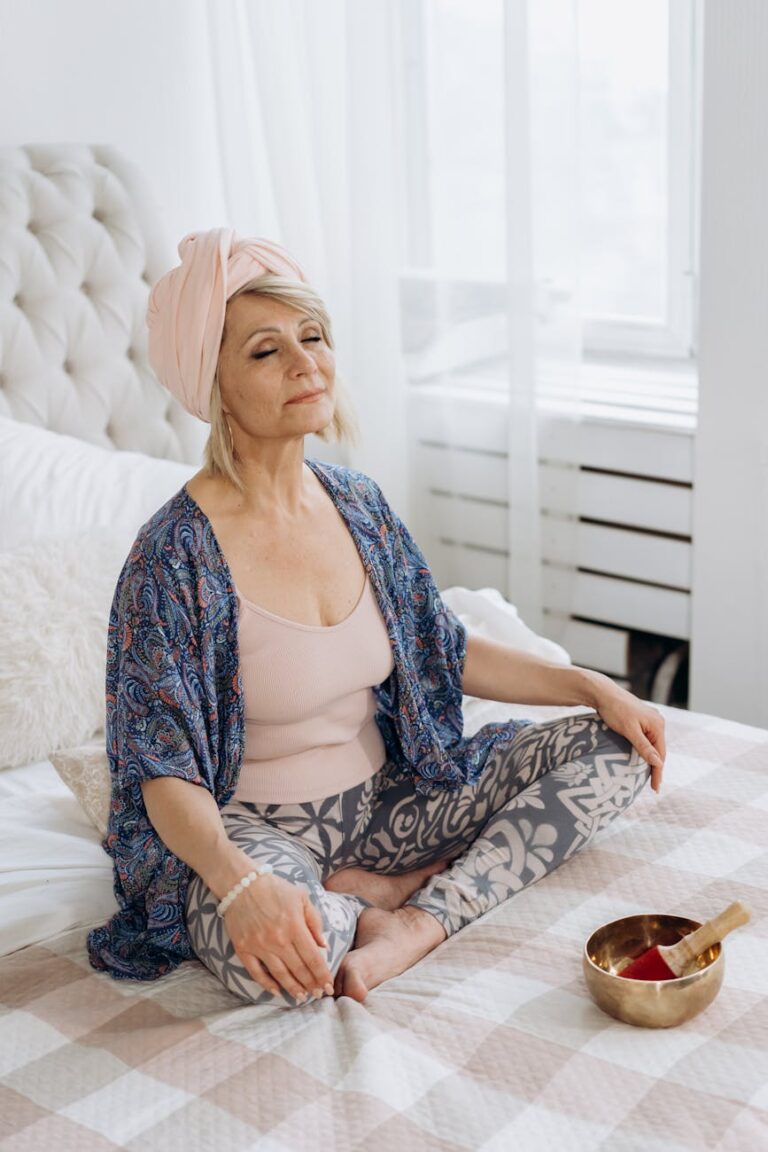 a woman meditating while sitting on the bed