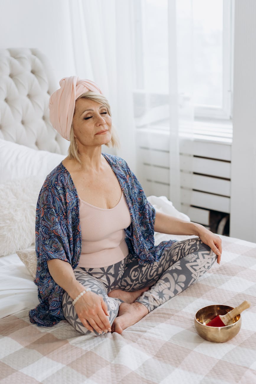 a woman meditating while sitting on the bed