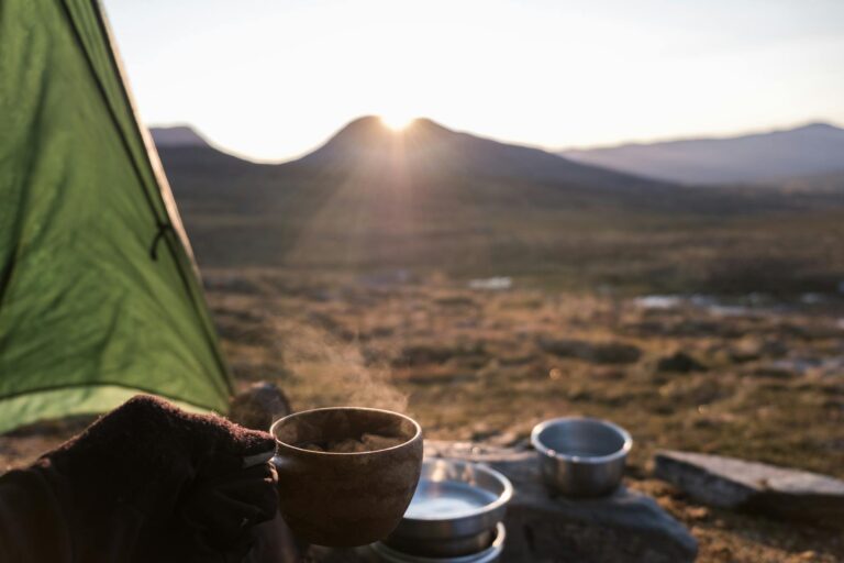 a person wearing gloves holding a cup of hot coffee